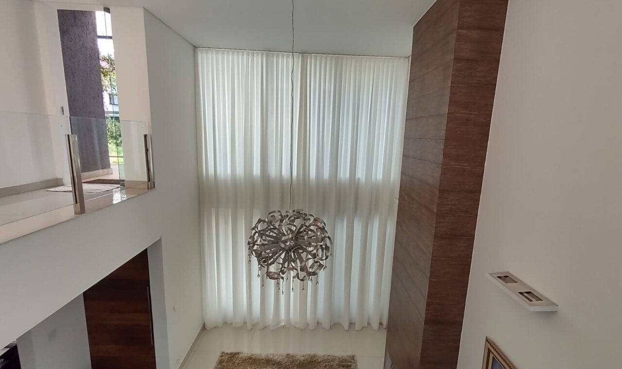 Cortina translúcida em sala com pé-direito duplo: a automação permite controlar a entrada de luz com um comando.