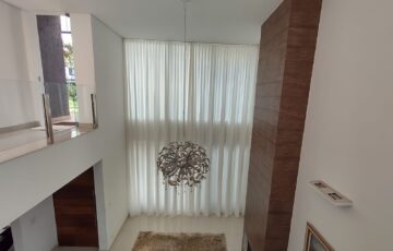 Cortina translúcida em sala com pé-direito duplo: a automação permite controlar a entrada de luz com um comando.